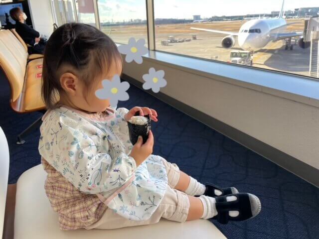 羽田空港で搭乗前におにぎりを食べて腹ごしらえする娘の写真